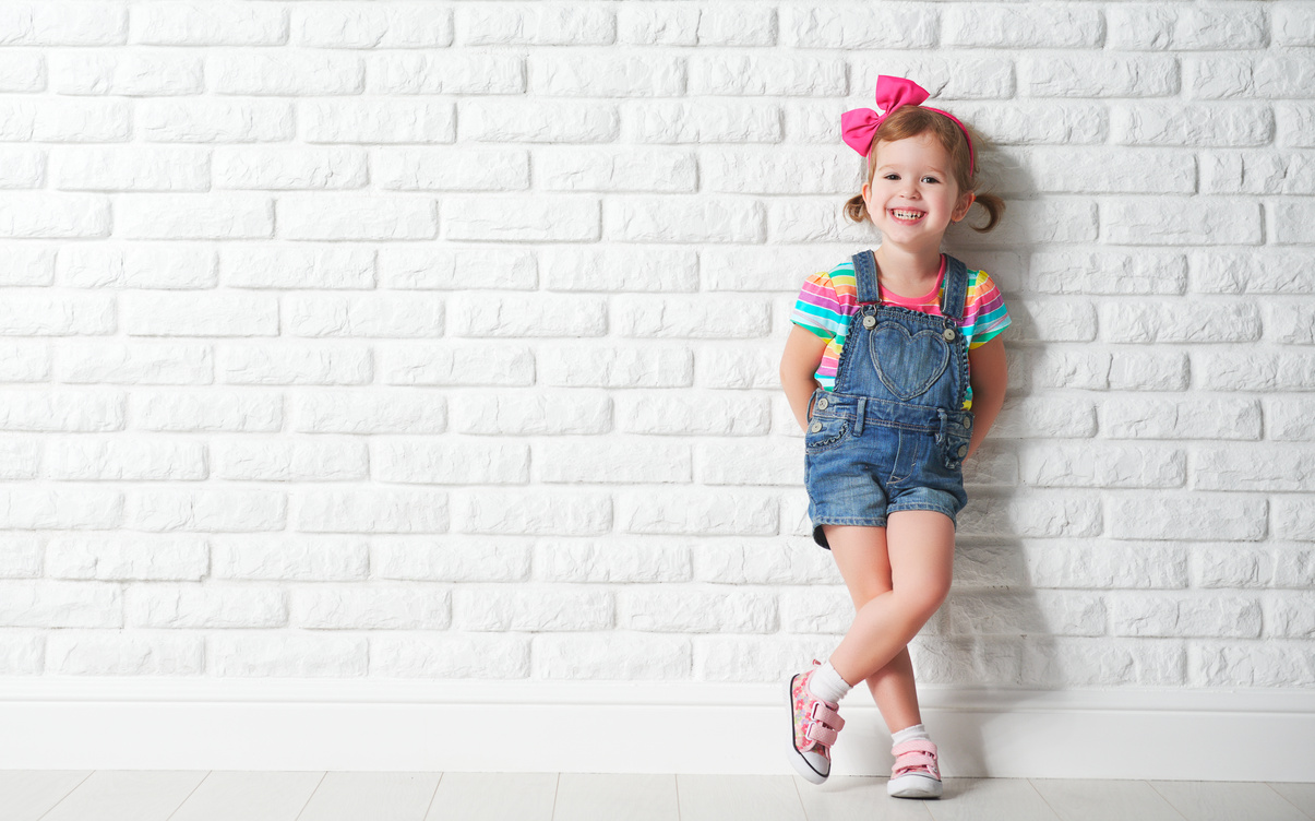 Happy child little girl laughing at blank brick wall