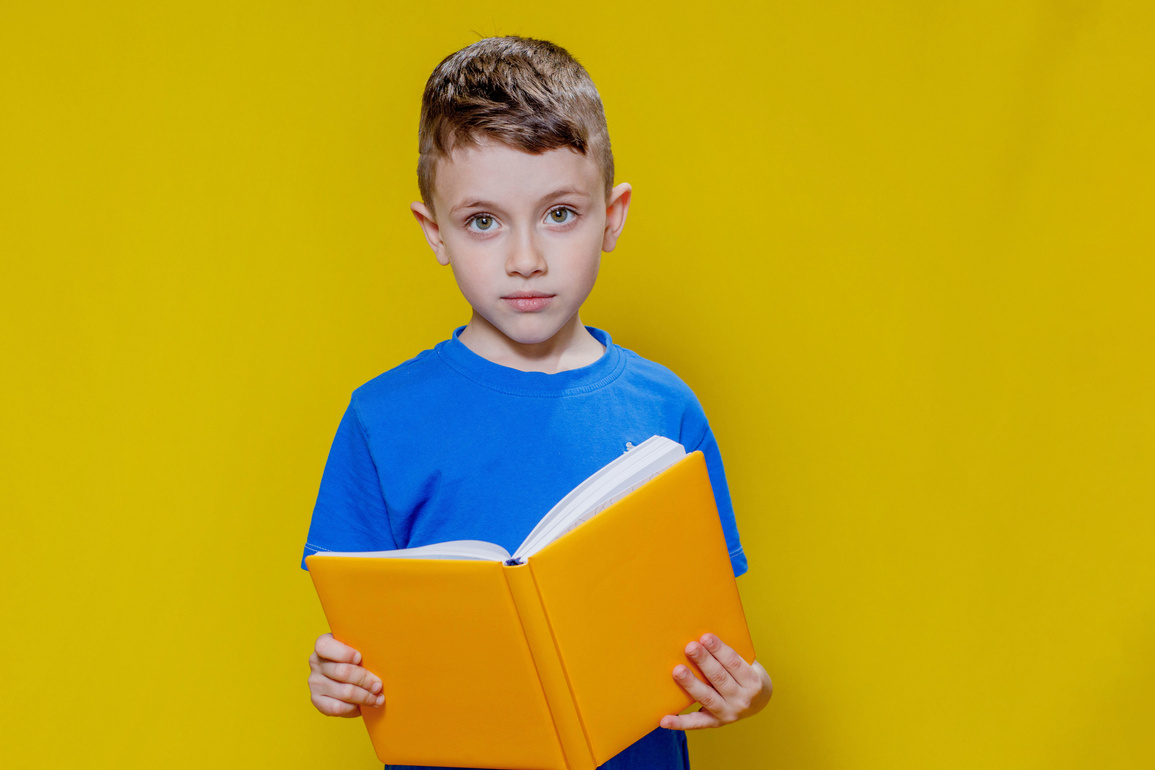 Positive preschool boy in an blueT-shirt holding an open yel